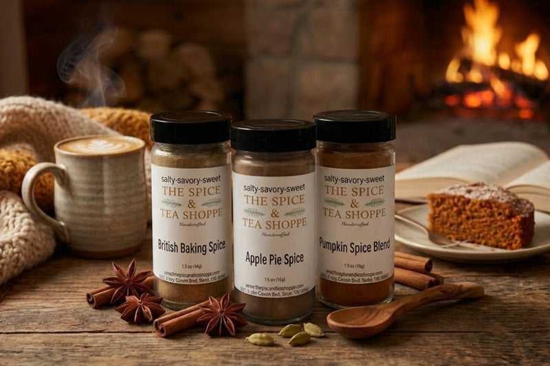Three fall spice jars beside a warm latte, cinnamon, and a cozy fireplace.