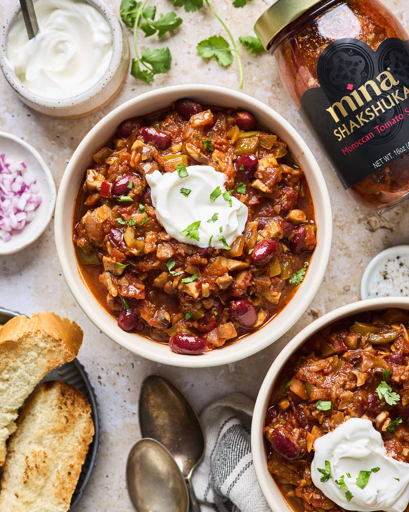 Two bowls of chili with toppings and a jar of salsa on a table. The Spice & Tea Shoppe