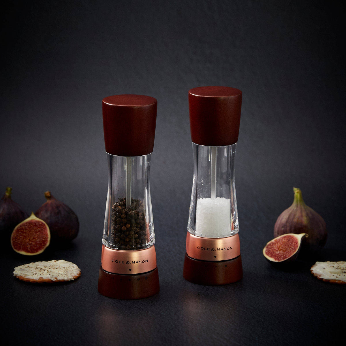 A pair of Cole & Mason Derwent salt and pepper mills featuring dark wood tops and bases with rose gold accents.