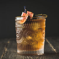 Bourbon and Fig Conserve Cocktail in cocktail glass on dark background, garnished with a fresh fig. The Spice & Tea Shoppe