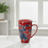 Red tea mug with lid and infuser with blue dragon design on a white surface. the spice and tea shoppe