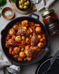 Skillet of chicken and vegetables with a jar of Mina Shakshuka on a table. The Spice & Tea Shoppe