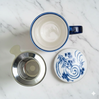 Blue mug with white interior, metal filter, and decorative lid on a marble surface