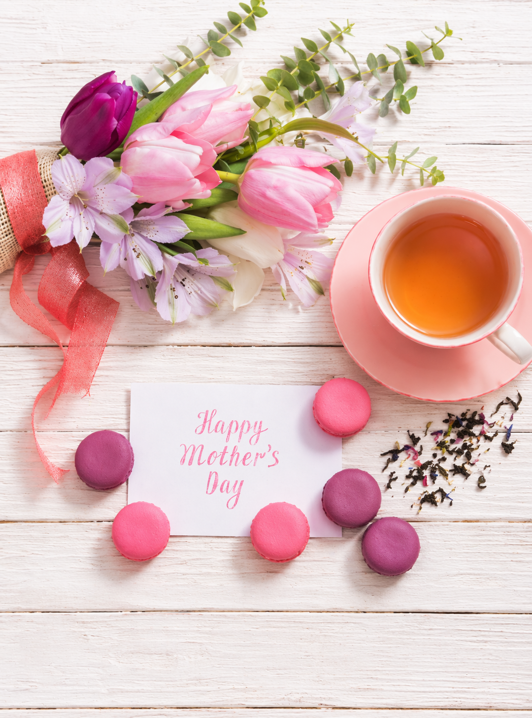 Mother's Day card with flowers, tea, and macarons on a wooden surface